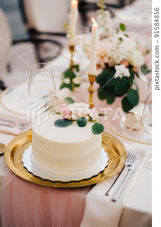 White wedding cake covered with white glaze stands on the table 91584856