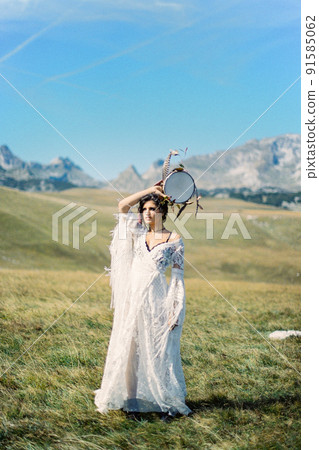 Girl with a tambourine in her hand stands in a green valley Girl with a tambourine in her hand stands in a green valley 91585062