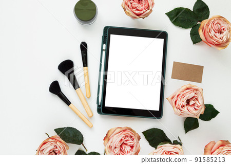 Creative workplace layout with blank screen tablet, flowers, business card. Female workspace mockup 91585213