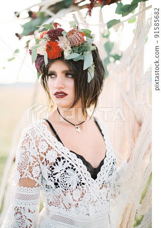 Bride in a wreath stands near the wedding arch 91585682