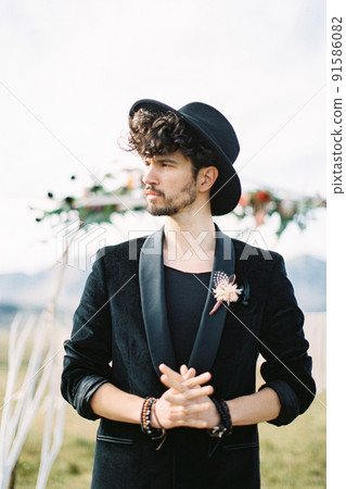 Groom in the black hat crossed his fingers and turned his head. Close-up Groom in the black hat crossed his fingers and turned his head. Close-up 91586082