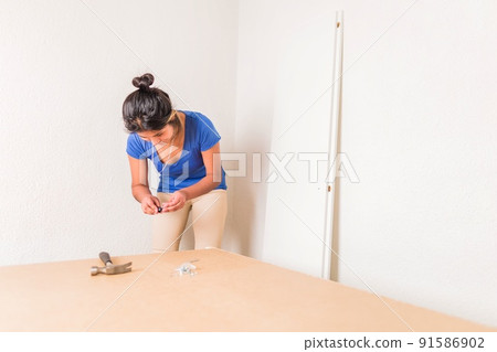 Latin Bolivian strong and independent success woman assembly and repair furniture with hammer. Latin Bolivian strong and independent success woman assembly and repair furniture with hammer. 91586902