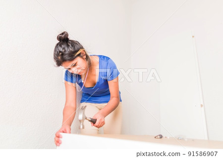 Latin Bolivian strong and independent success woman assembly and repair furniture with hammer. Latin Bolivian strong and independent success woman assembly and repair furniture with hammer. 91586907