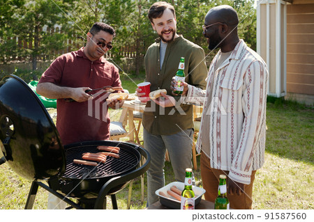 Three happy young intercultural men having beer and chat outdoors 91587560