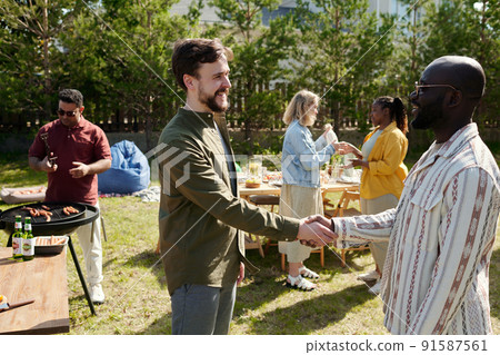 Two happy young intercultural men greeting each other by handshake 91587561