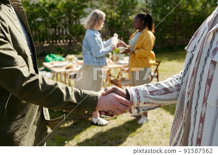 Handshake of two young interracial men greeting each other during outdoor party 91587562