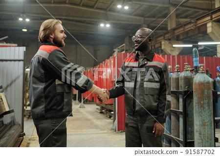 Two young confident male engineers shaking hands after negotiating 91587702