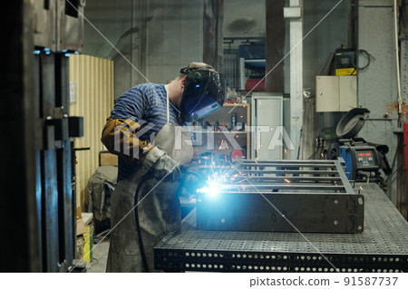 Side view of male worker of huge industrial plant or manufactory Side view of male worker of huge industrial plant or manufactory 91587737