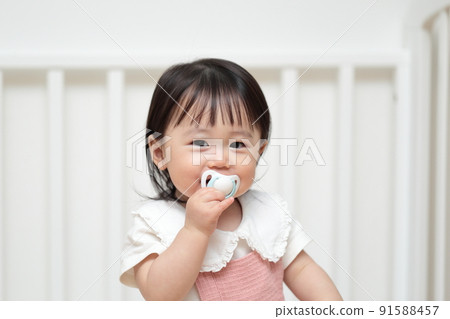 1 year old girl playing with a pacifier toy 91588457