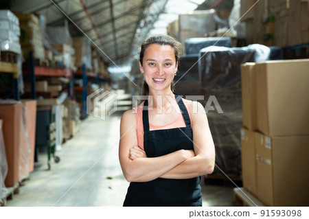 Female in apron standing near shelves with cardboard boxes for packaging Female in apron standing near shelves with cardboard boxes for packaging 91593098