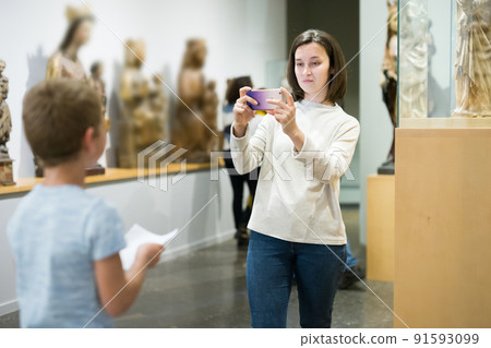 Woman using phone in museum Woman using phone in museum 91593099