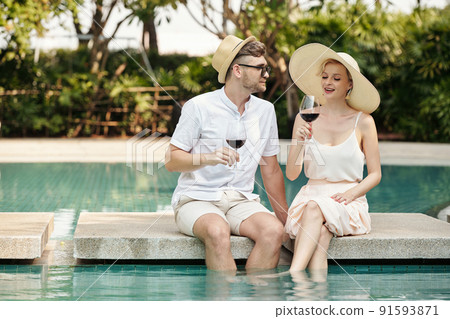 Couple Relaxing At Poolside Couple Relaxing At Poolside 91593871