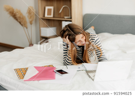 A tired student is preparing for a difficult exam at home using a laptop. Modern technologies of training and education A tired student is preparing for a difficult exam at home using a laptop. Modern technologies of training and education 91594025