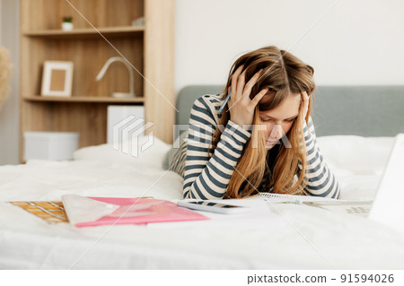 A tired student is preparing for a difficult exam at home using a laptop. Modern technologies of training and education 91594026