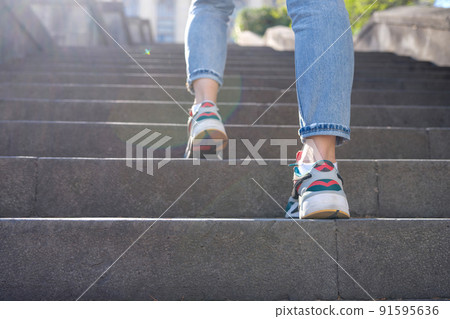 Female tourist in casual clothes going upstairs outdoors 91595636