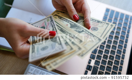 Woman holding cash in hand and counting banknotes Woman holding cash in hand and counting banknotes 91595732