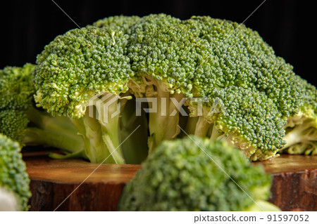 Raw green broccoli florets on a wooden board with ingredients. Close-up Raw green broccoli florets on a wooden board with ingredients. Close-up 91597052