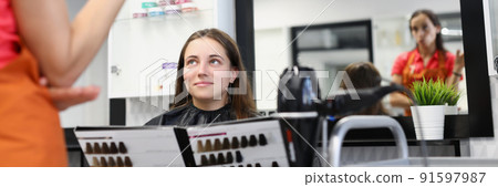 Pretty woman client hold palette of colours for hair dye at hairdresser appointment Pretty woman client hold palette of colours for hair dye at hairdresser appointment 91597987