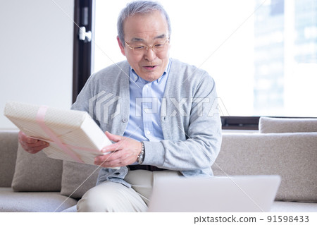 視頻通話：一位老人打開了寄給他的禮物，他的家人在線連接。 91598433