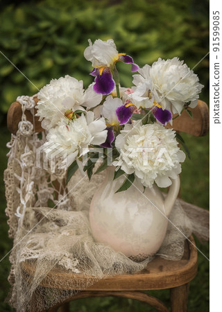 Bouquet of bearded irises and white peonies on a chair. Bouquet of bearded irises and white peonies on a chair. 91599085