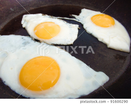 3 fried eggs frying in a pan with olive oil. Three fried eggs in cast iron frying pan sprinkled with ground black. 3 fried eggs frying in a pan with olive oil. Three fried eggs in cast iron frying pan sprinkled with ground black. 91600290