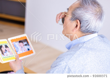 Grandpa drinking alcohol while looking at his grandson's photo 91600371