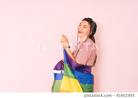 Laughing girl with rainbow flag against pink background Laughing girl with rainbow flag against pink background 91602995