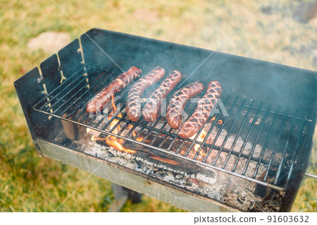 Delicious sausage on grill with spices and herbs on the flaming grill. Delicious sausage on grill with spices and herbs on the flaming grill. 91603632