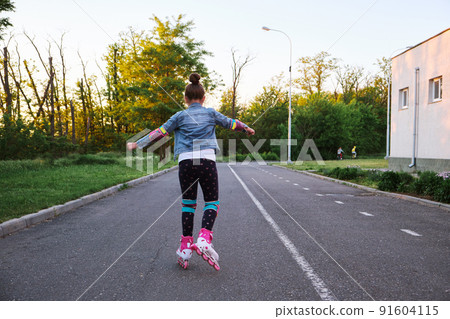 Girl riding roller skates in the park Girl riding roller skates in the park 91604115