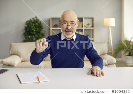 Experienced senior man talks and conducts online client counseling while sitting in home office. 91604323