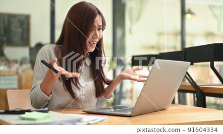 Upset young female employee having problems with laptop, solving business problem Upset young female employee having problems with laptop, solving business problem 91604334