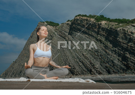 Yoga practice and meditation in nature. Woman practicing near Black sea. 91604675