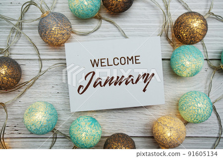 Welcome January text on paper card with LED cotton balls top view on wooden background Welcome January text on paper card with LED cotton balls top view on wooden background 91605134