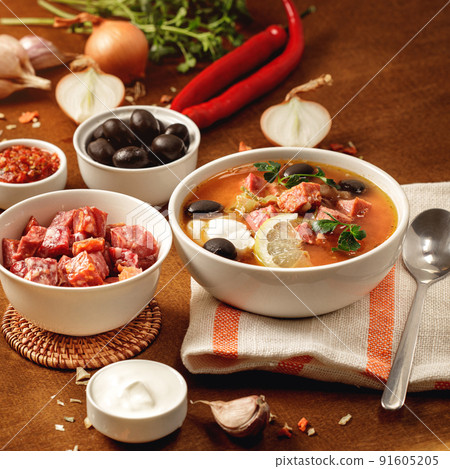 Meat Solyanka soup on with ingridients, sausage, olive,lemon, parsley, garlic, yogurt. Ukrainian food. Wooden background. Meat Solyanka soup on with ingridients, sausage, olive,lemon, parsley, garlic, yogurt. Ukrainian food. Wooden background. 91605205