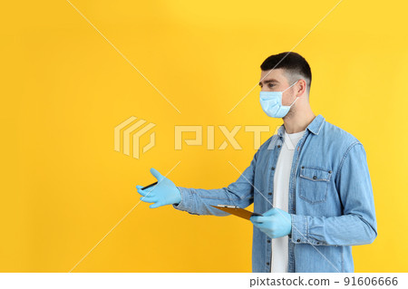 Delivery man with clipboard and pen on yellow background Delivery man with clipboard and pen on yellow background 91606666