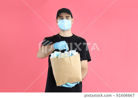 Delivery man holds bag with medicines on pink background Delivery man holds bag with medicines on pink background 91606667