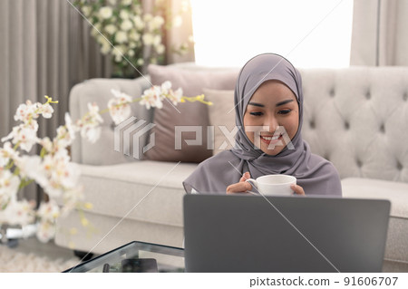 Muslim young women wear hijab using computer laptop at home morning. Concept business small and shop online Muslim young women wear hijab using computer laptop at home morning. Concept business small and shop online 91606707