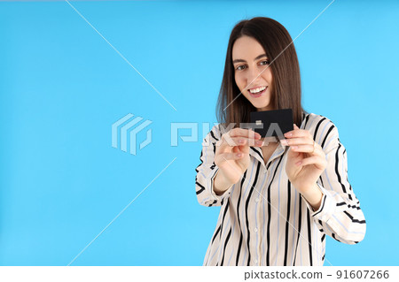 Attractive woman with card on blue background Attractive woman with card on blue background 91607266