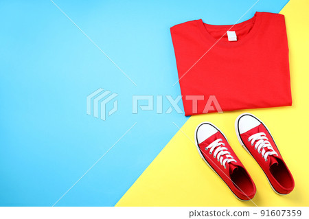 Blank t-shirt and sneakers on two tone background 91607359