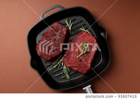 Concept of cooking with raw beef steaks on brown background Concept of cooking with raw beef steaks on brown background 91607418