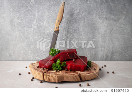 Concept of cooking with raw beef steaks against gray textured background Concept of cooking with raw beef steaks against gray textured background 91607420