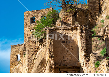 ruins of stone houses attached to the rock in the depopulated village of Gamsutl in Dagestan 91607811