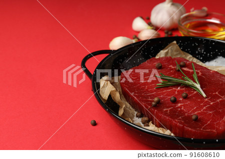 Concept of cooking with raw steak on red background 91608610