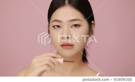 Close up face of beautiful young Asian woman applying lip on her lips on pink background. Close up face of beautiful young Asian woman applying lip on her lips on pink background. 91609108