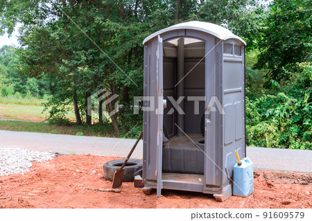 On a construction site, workers use a portable restroom 91609579