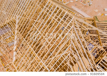 Timber frame beam framework house under construction with wooden trusses aerial view Timber frame beam framework house under construction with wooden trusses aerial view 91609584