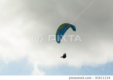 Paraglider flying over clouds in summer day 91611134