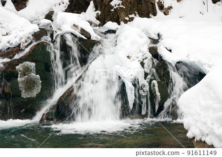 A small active waterfall. Clean mountain stream, snowy winter landscape, wildlife background A small active waterfall. Clean mountain stream, snowy winter landscape, wildlife background 91611149