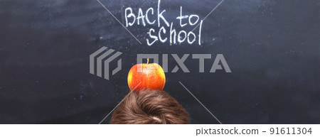 an apple on a child's head near chalkboard. Back to school concept background an apple on a child's head near chalkboard. Back to school concept background 91611304