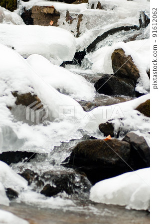 A small active waterfall. Clean mountain stream, snowy winter landscape, wildlife background 91612062